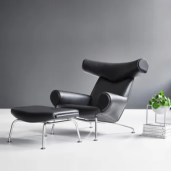 Гостиная в современном гостиничном стиле с мягким креслом из черной кожи, односпальным диваном-креслом со скамеечкой для ног